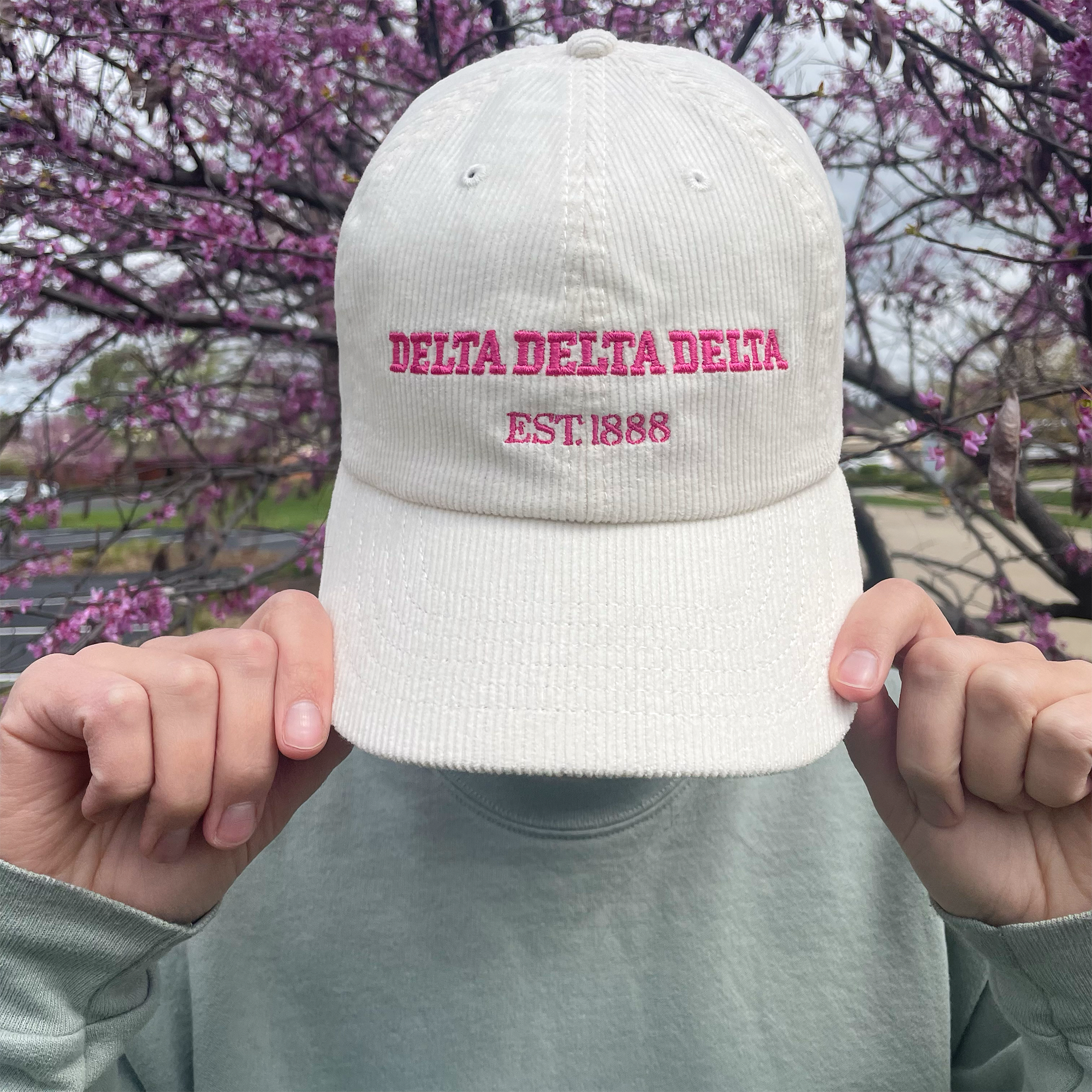 a person holding up a hat with the word delta delta on it