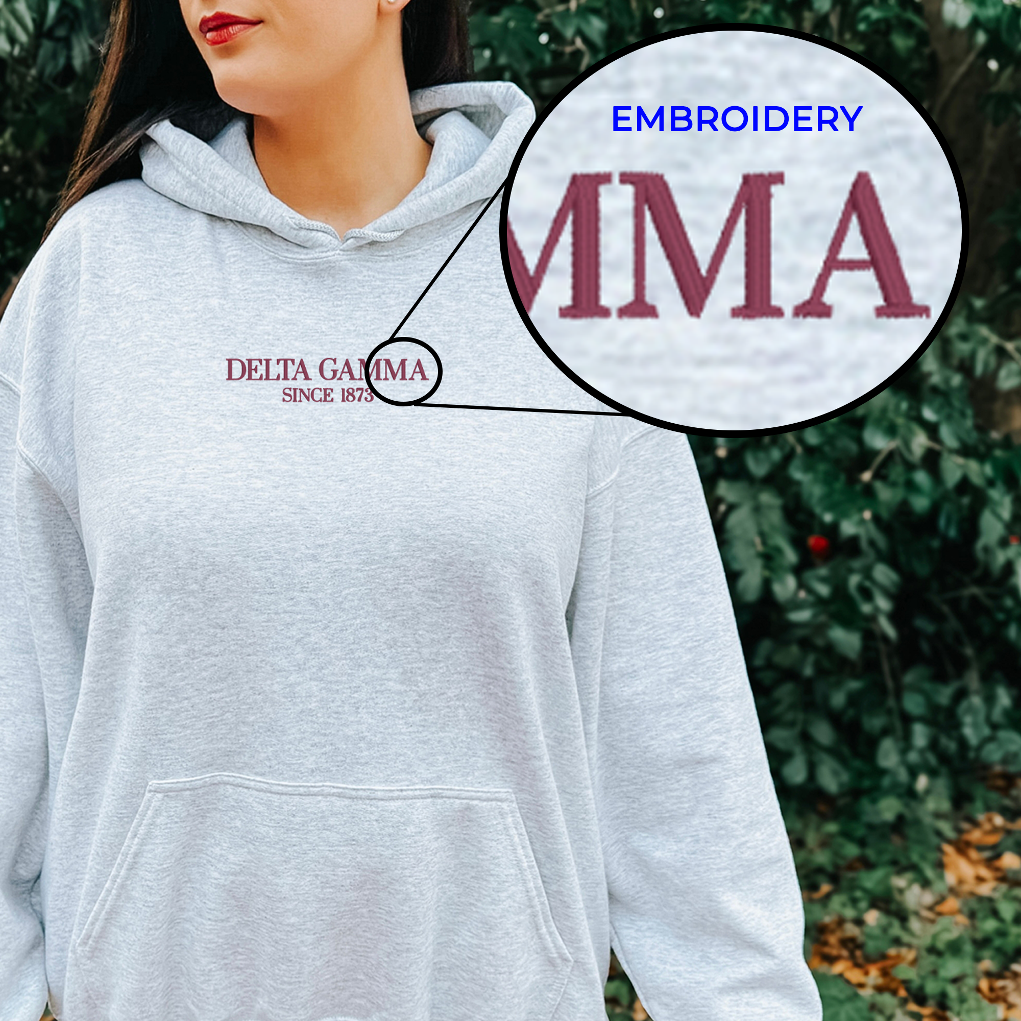 A woman wearing a grey hoodie with the Delta Gamma logo embroidered on it.