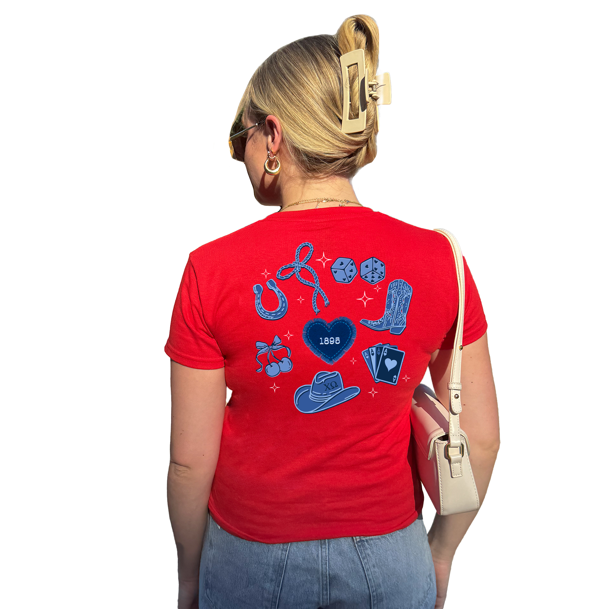 A woman wearing a red t-shirt with various symbols and icons printed on it, including a heart, horseshoes, and playing cards. She is also wearing sunglasses and has a white purse on her shoulder.