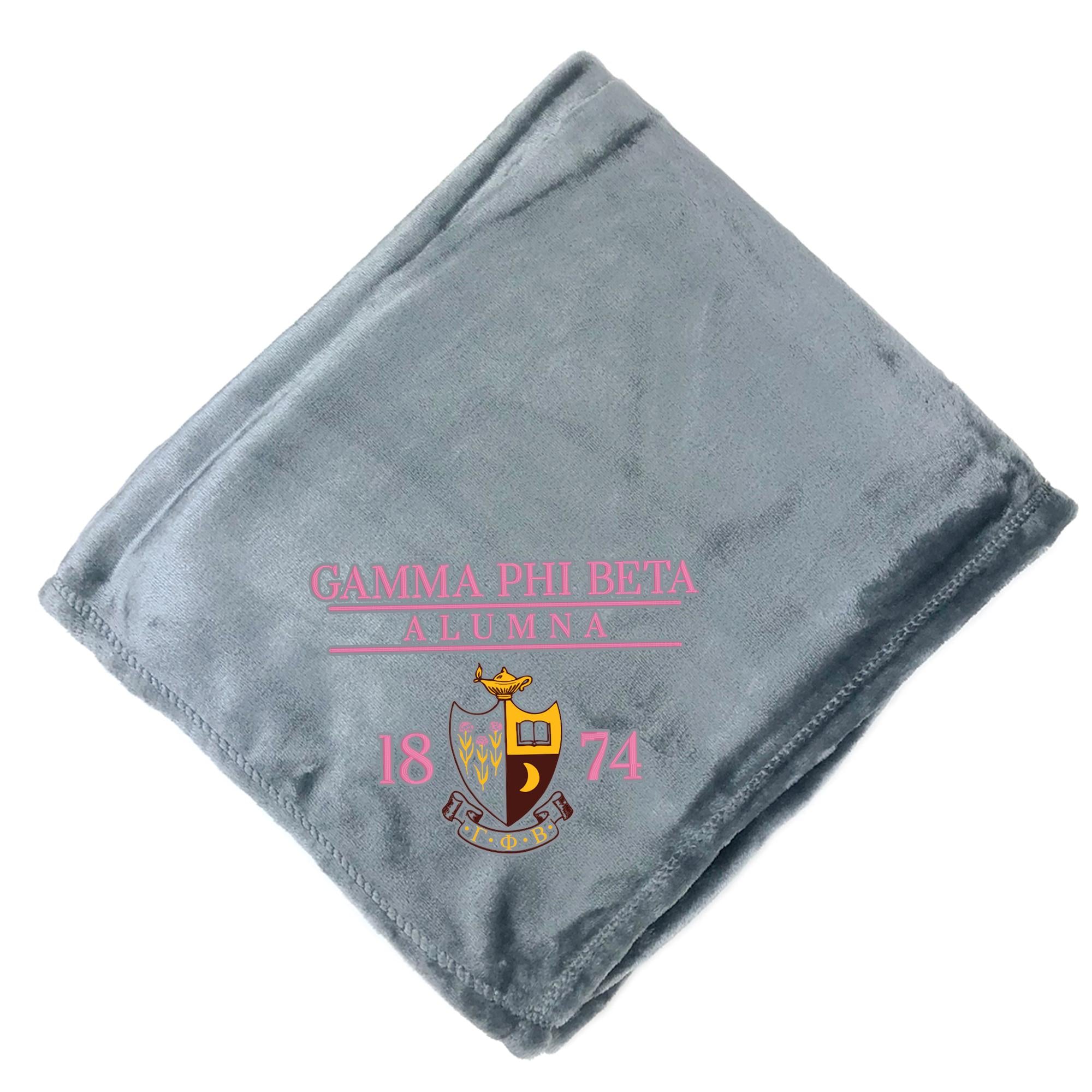 A gray fleece blanket with the text "GAMMA PHI BETA ALUMNA 1874" printed on it, along with a crest design.