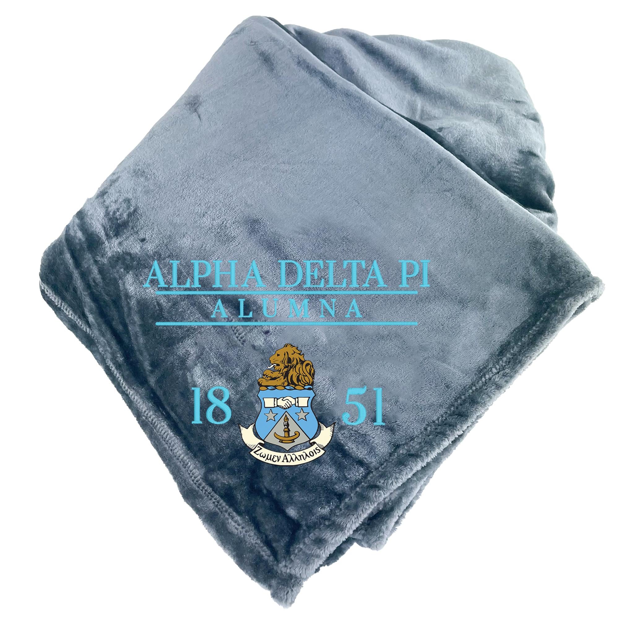 A gray fleece blanket with the text "ALPHA DELTA PI ALUMNA 18 51" printed on it, along with a crest design.