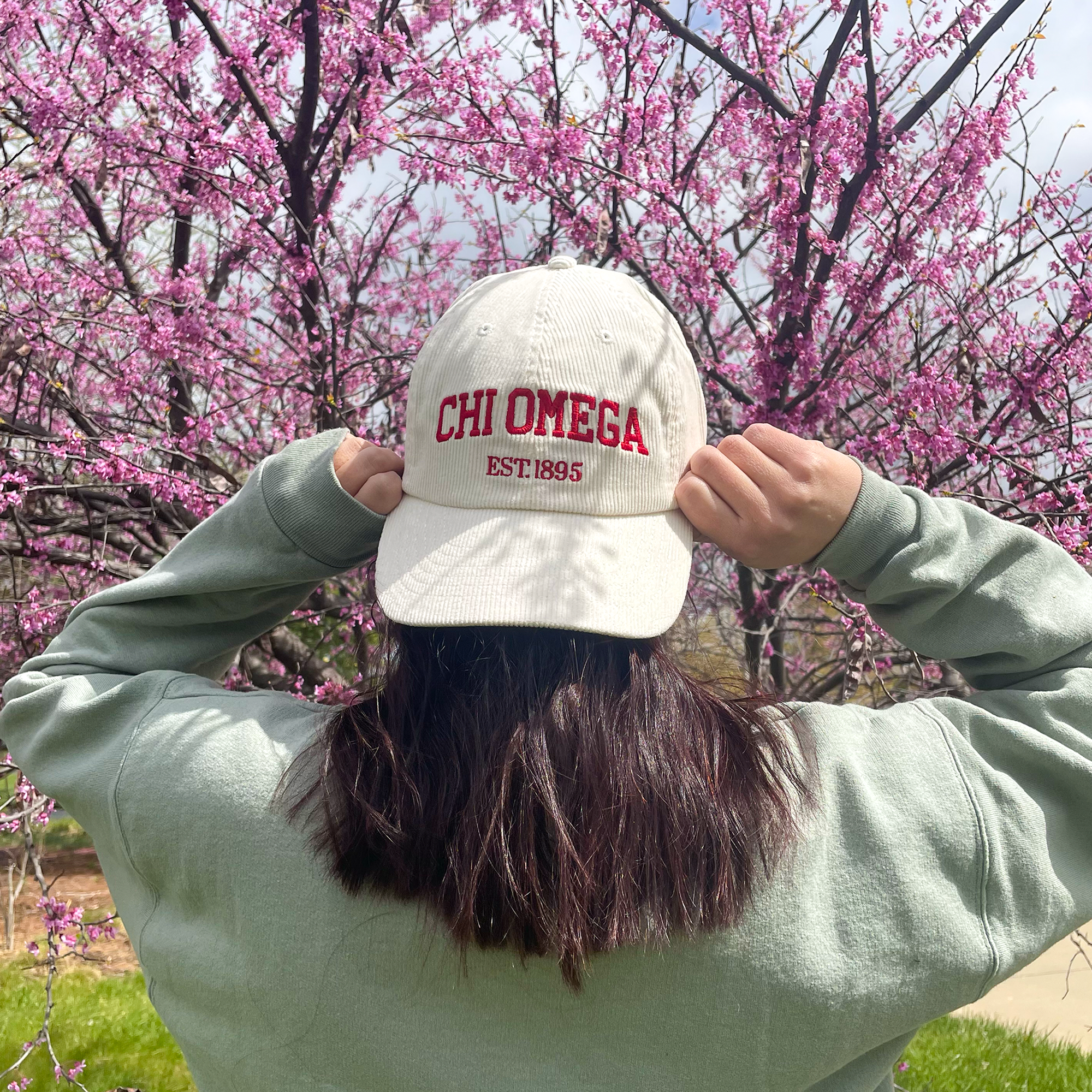 a person wearing a hat with the word chi omega on it