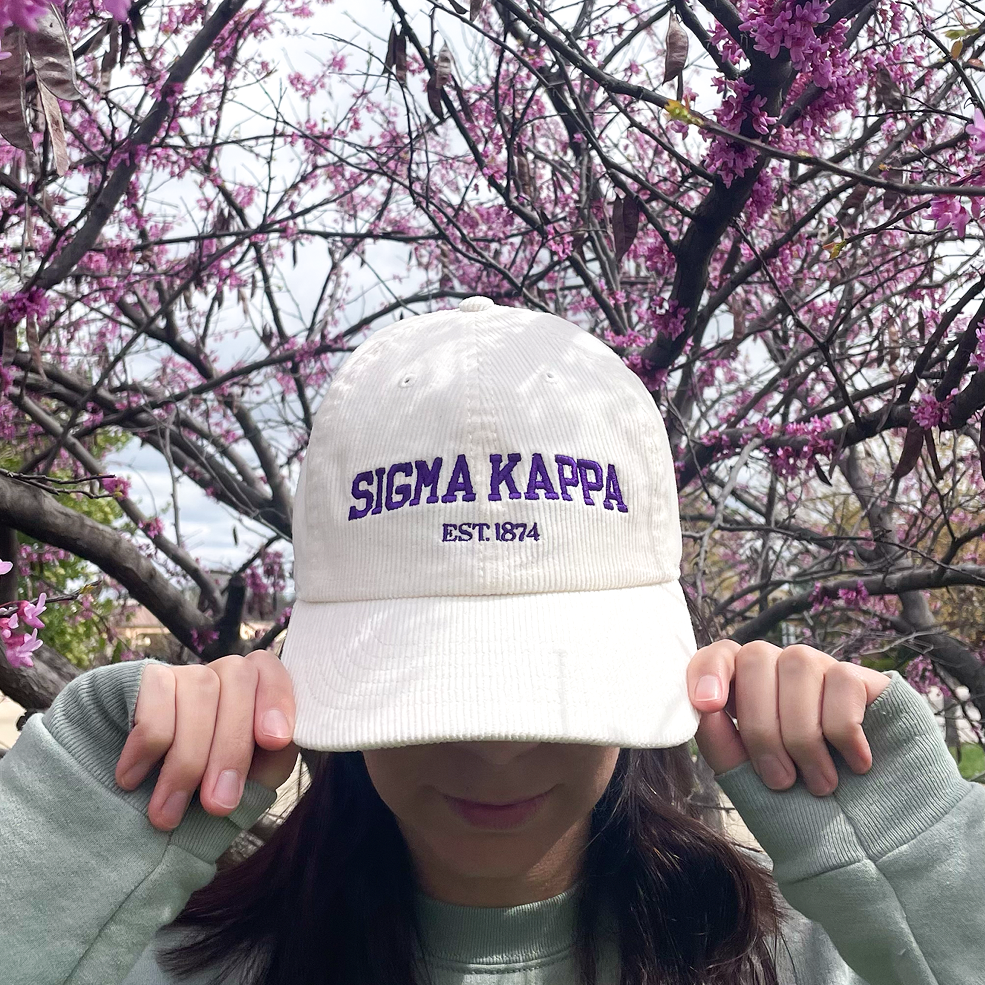 a woman wearing a white hat with the word signa kappa on it