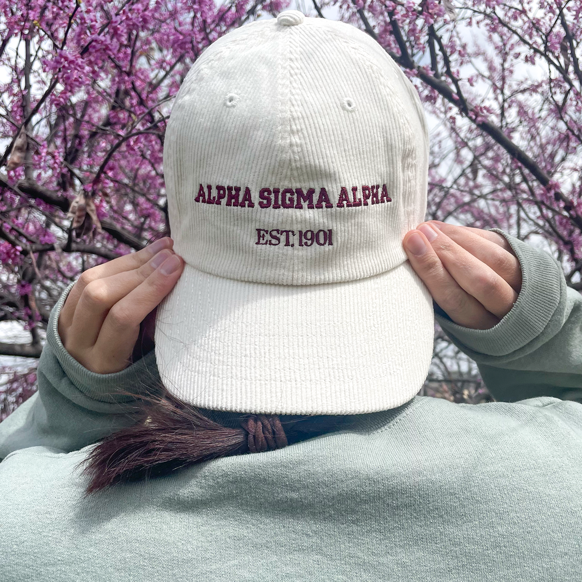 a person wearing a white hat with the words alpha stigma aloh embroidered on it