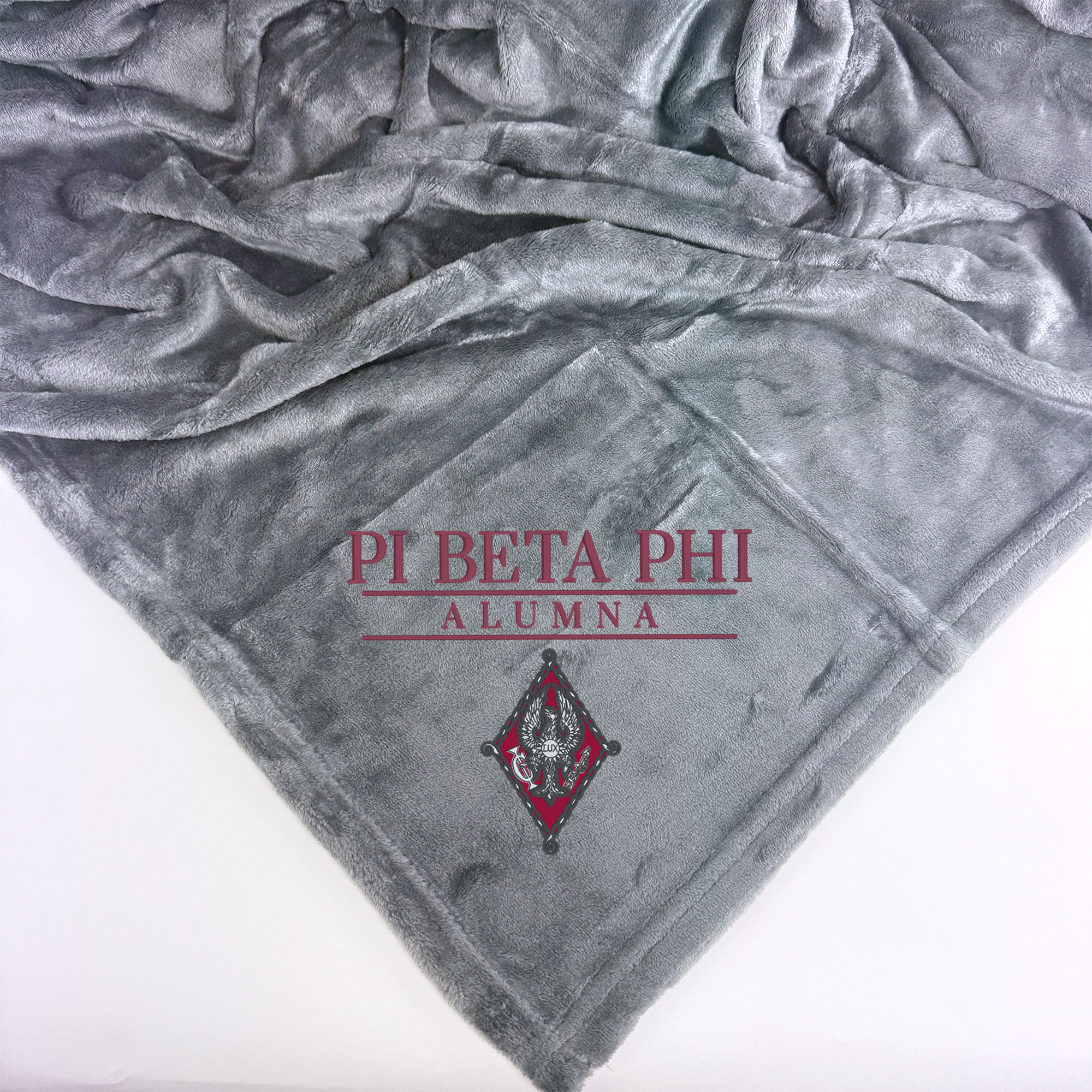 a gray blanket with the text "PI BETA PHI ALUMNA" printed on it.