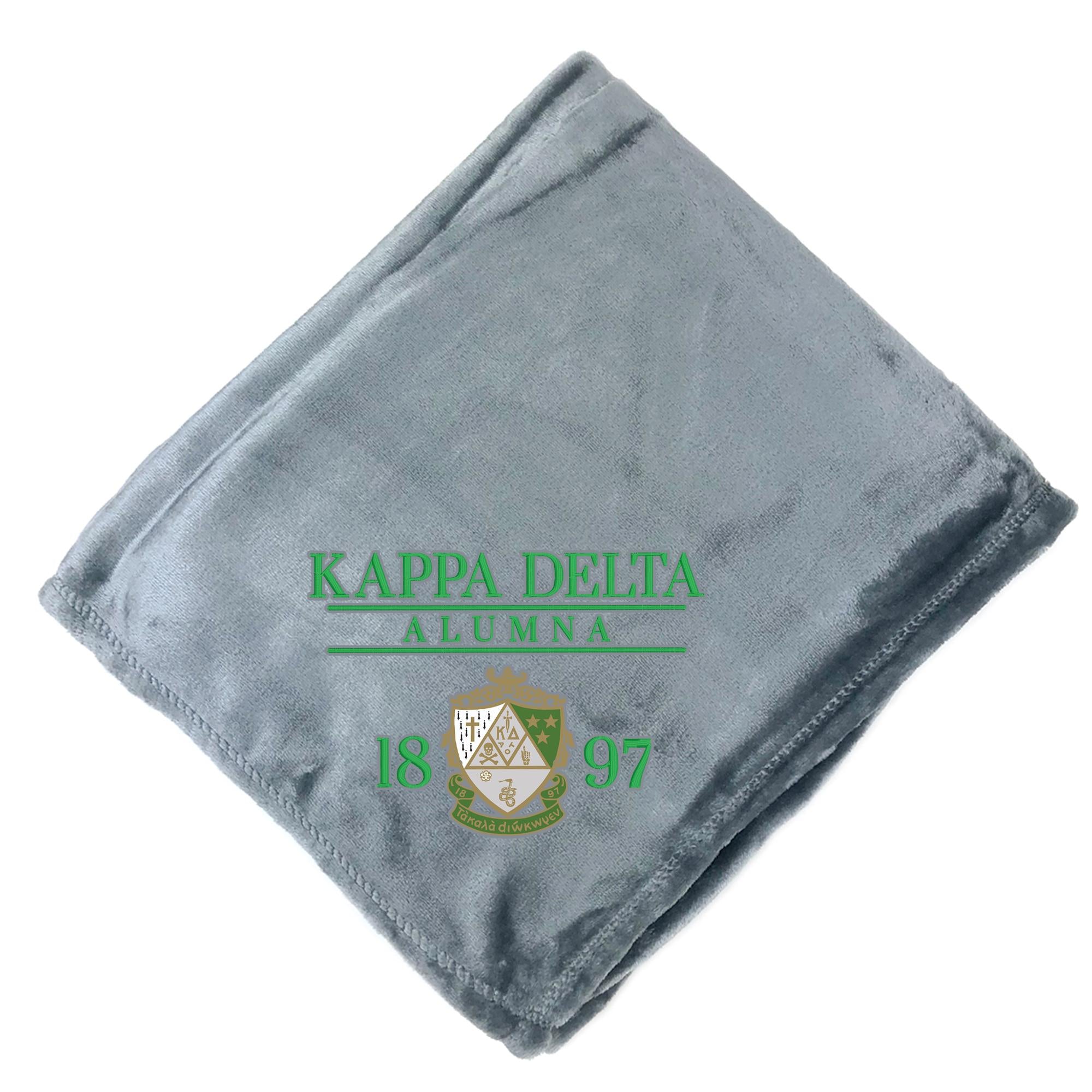 A gray fleece blanket with the text "KAPPADELTA ALUMNA 1897" printed on it.