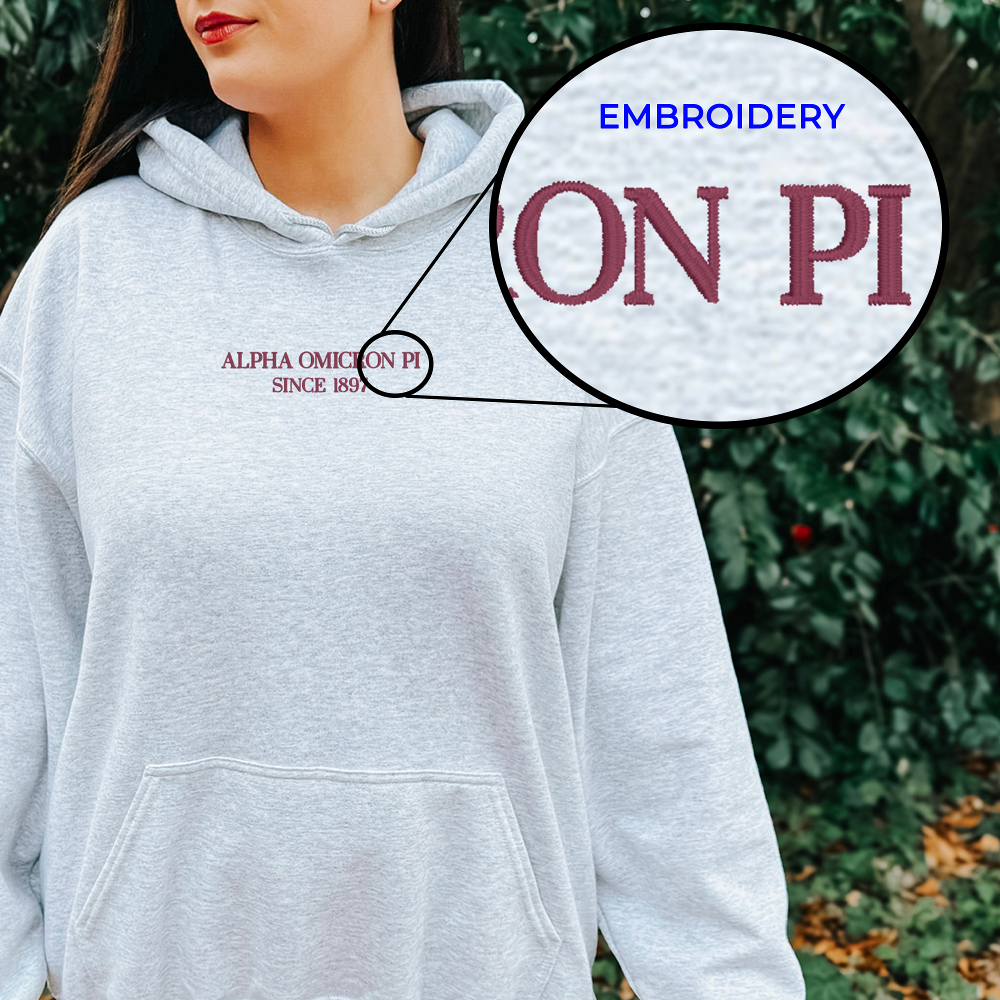A woman wearing a grey hoodie with the embroidered text "ALPHA OMICRON PI SINCE 1898" on it.