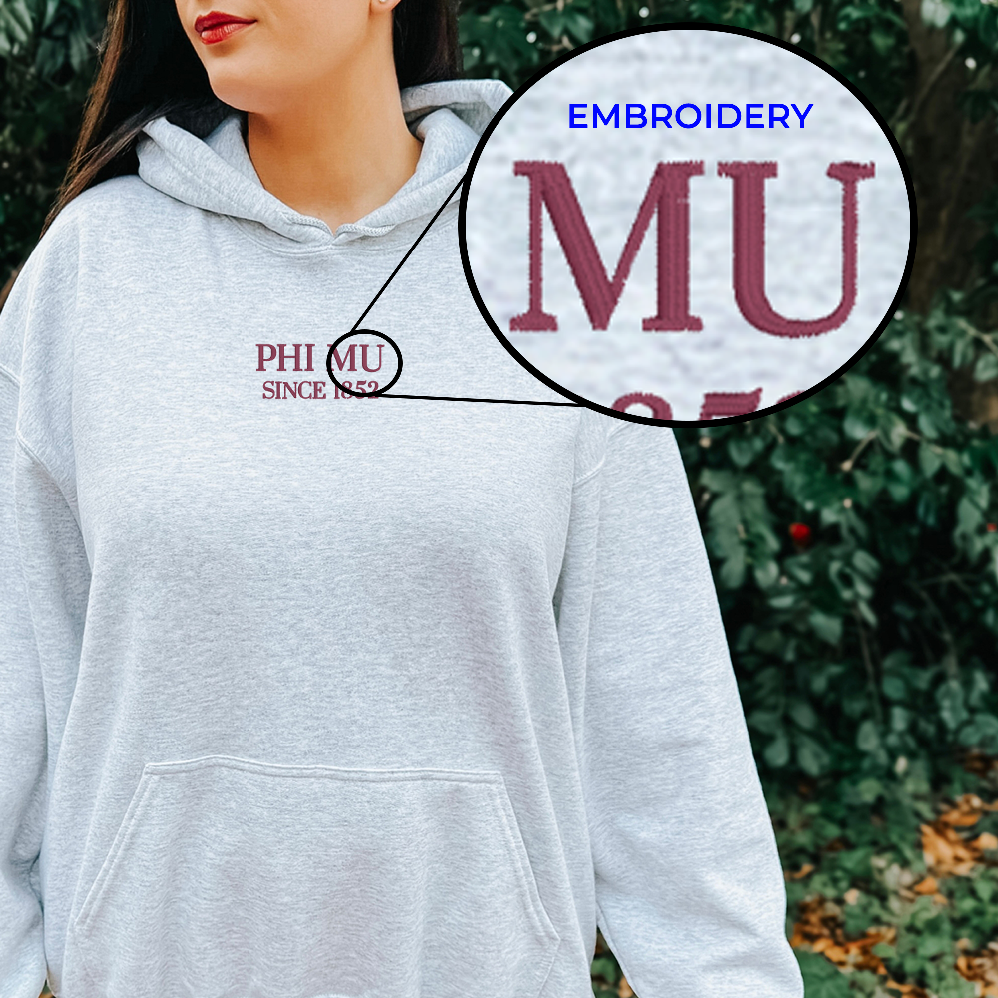 A woman wearing a grey hoodie with a red and white embroidered logo on the front.