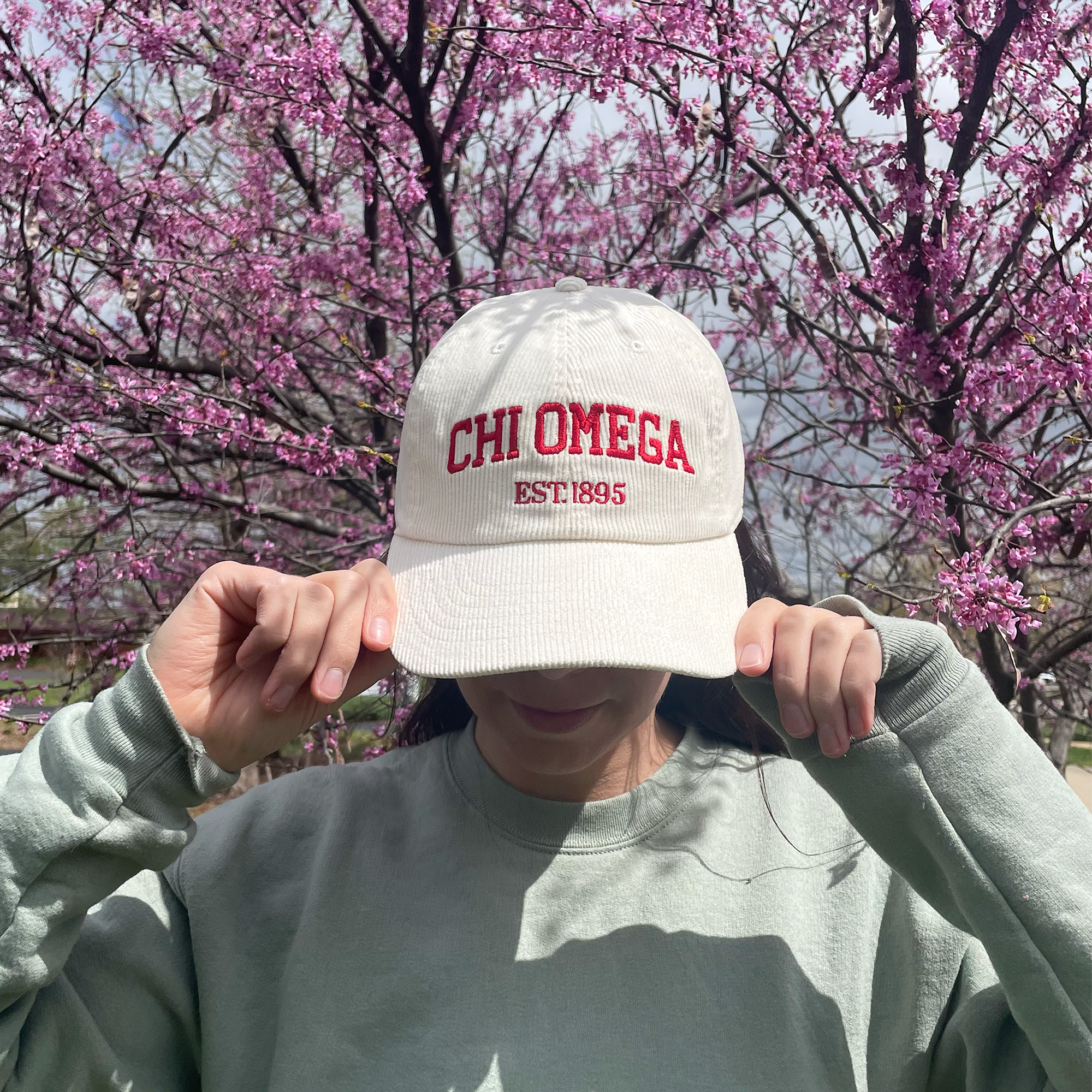 a girl wearing a hat with the word chi omega on it